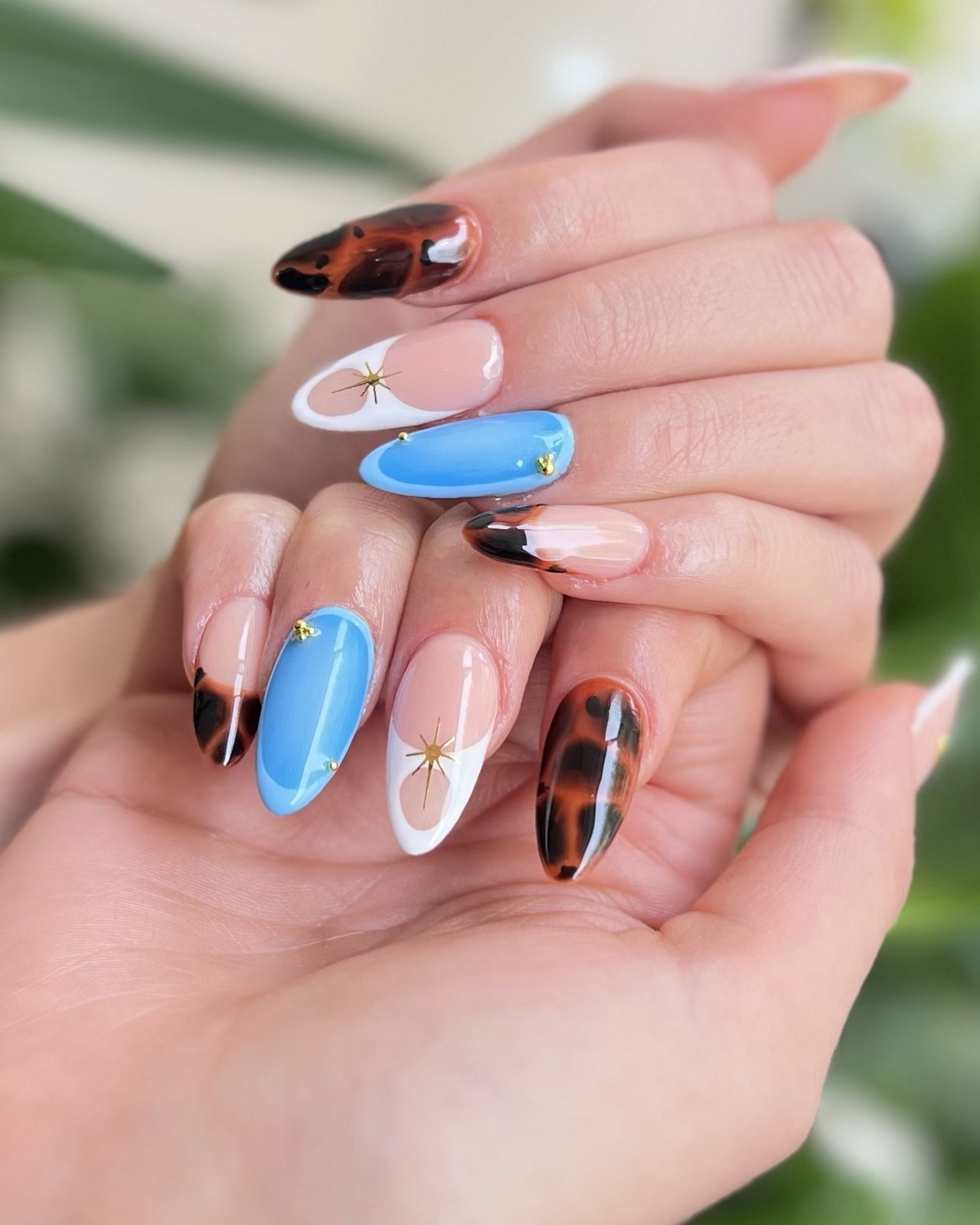 Ongles amande peints main : écaille brune, bleu azur et French blanche étoilée d'or. Maison Jolis Nails, Aix-en-Provence